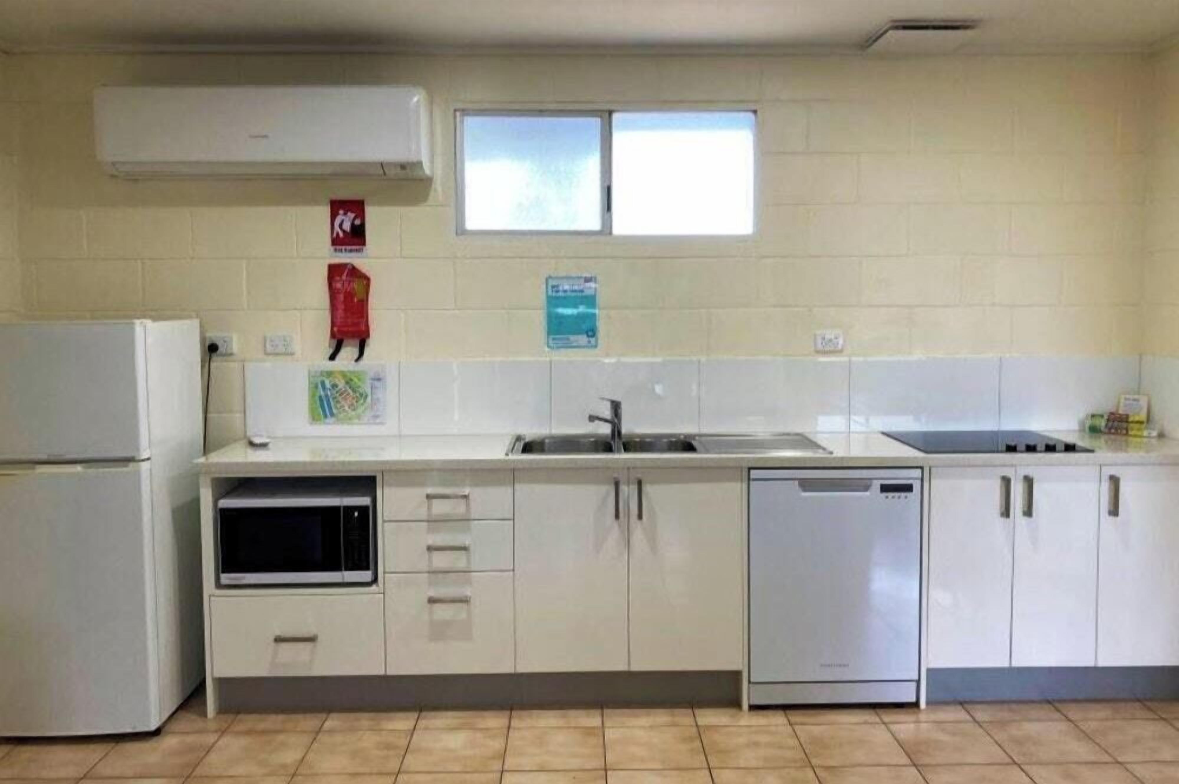 A kitchen with white cabinets, a dishwasher, a microwave, and a window above the sink.