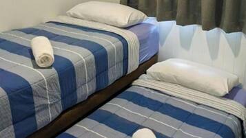 Two single beds with striped bedding, pillows, and a rolled-up towel.