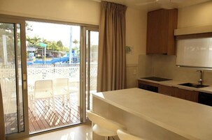 A modern kitchen with a large island, a sliding glass door leading to an outdoor deck, and a view of a water park.
