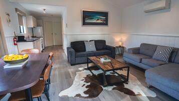 A modern living room with a dining area, a sofa set, a coffee table, and a cowhide rug.