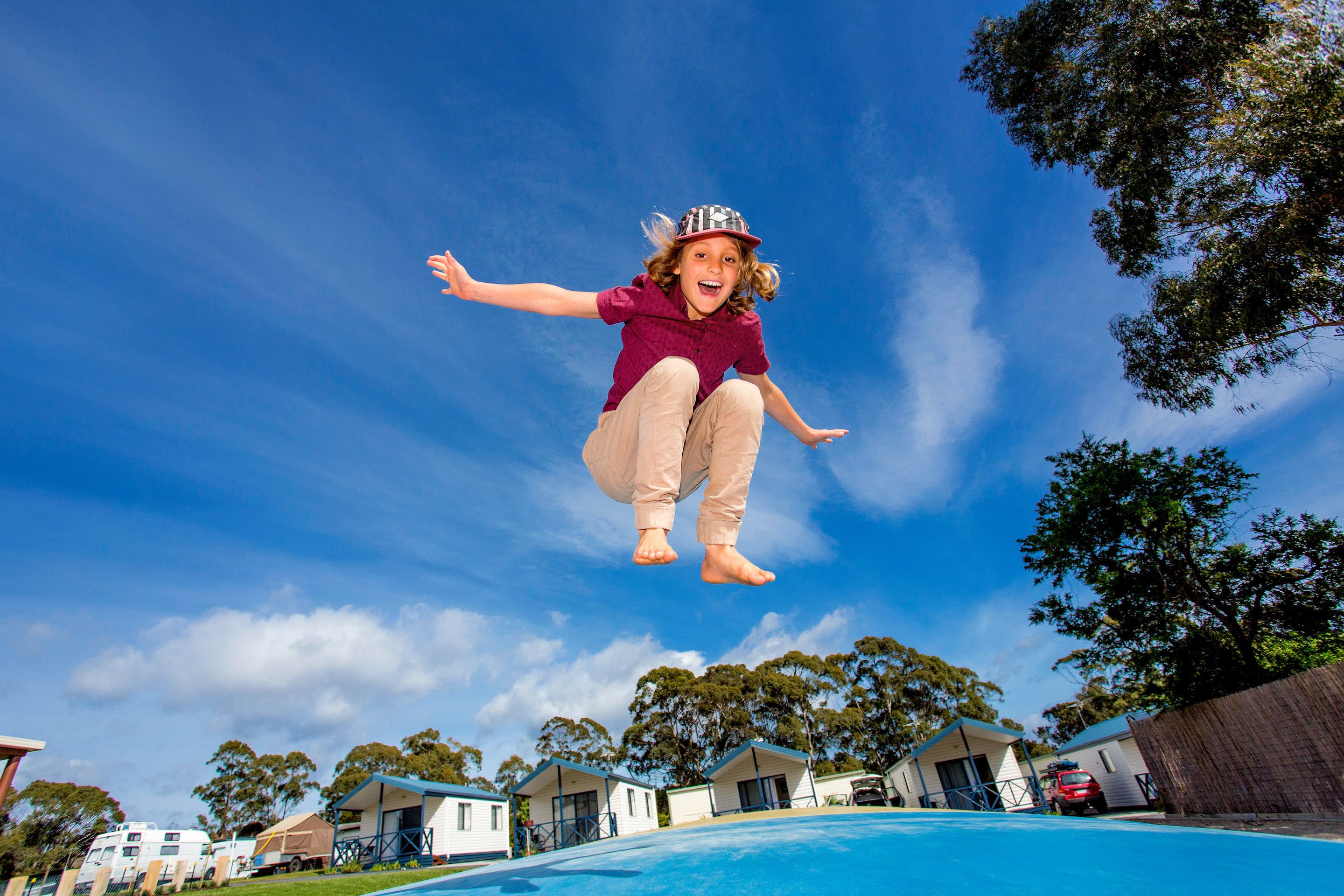 A person jumping off a pool with houses and trees in the background.