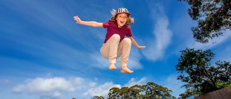 A person jumping off a pool with houses and trees in the background.