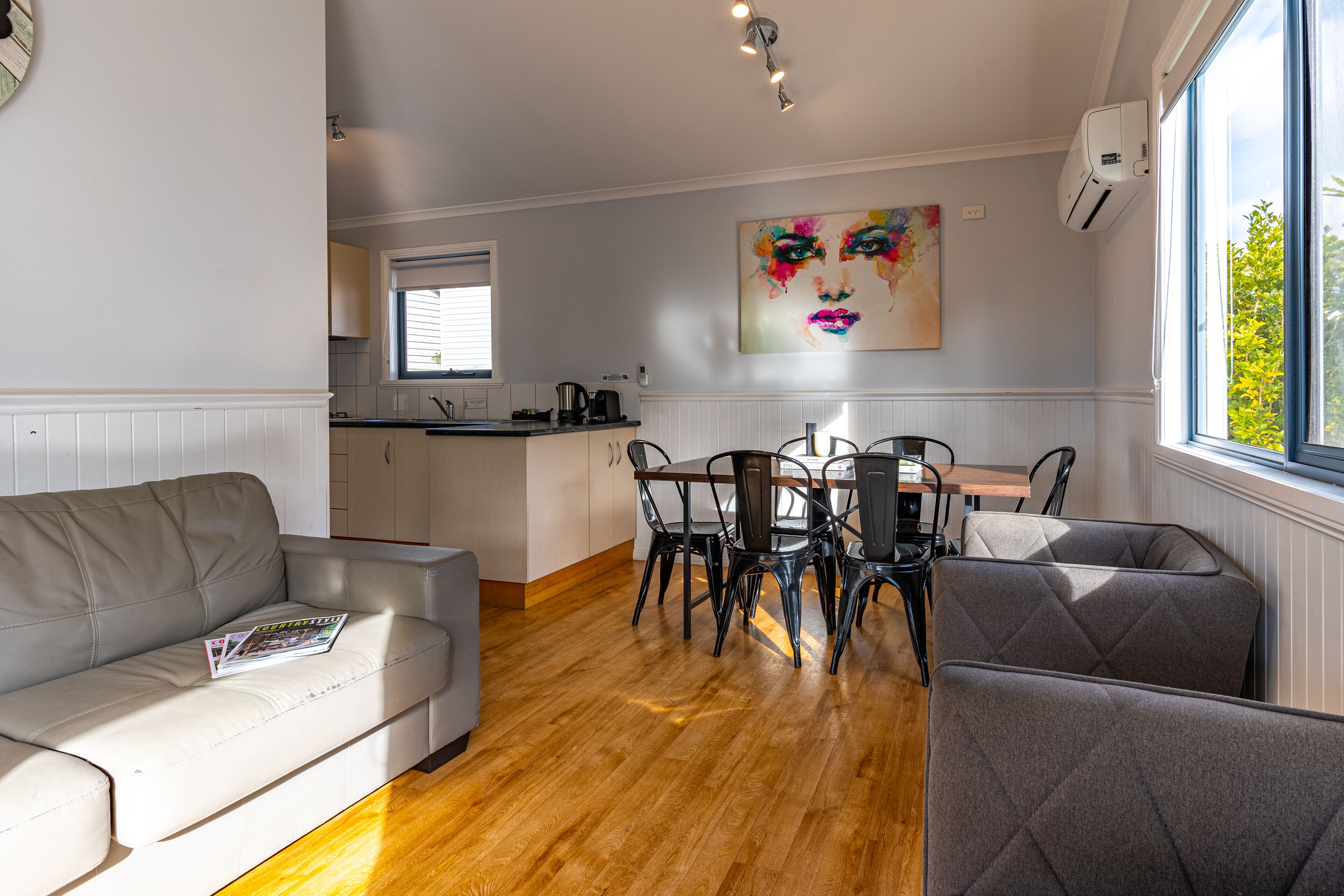 A modern kitchen with a dining area, featuring a white sofa, dining table, and chairs.