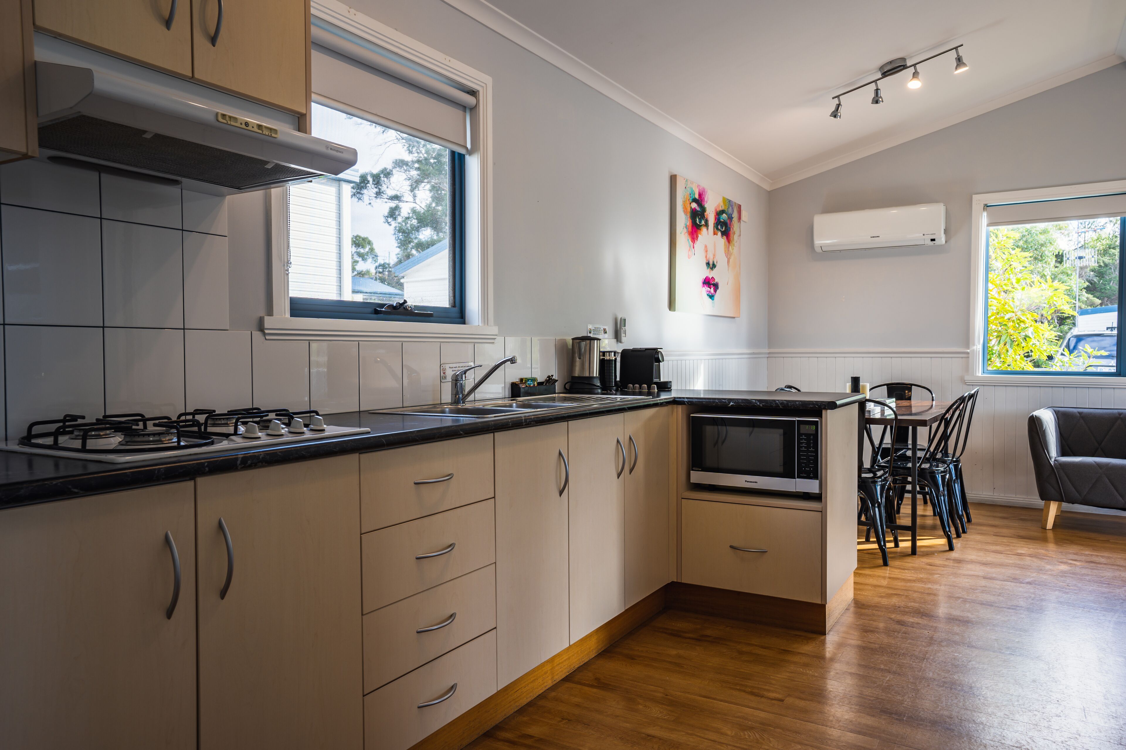 Una cocina moderna con armarios blancos, una estufa a gas y un comedor con mesa y sillas.