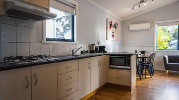 Una cocina moderna con armarios blancos, una estufa a gas y un comedor con mesa y sillas.