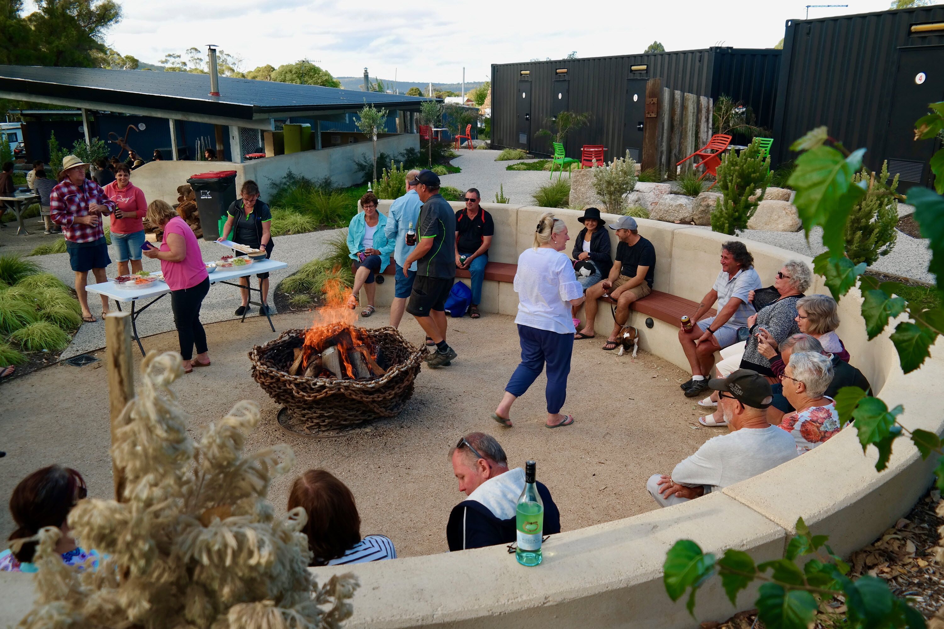 Un espacio al aire libre para reuniones con una chimenea, asientos y un jardín ajardinado.