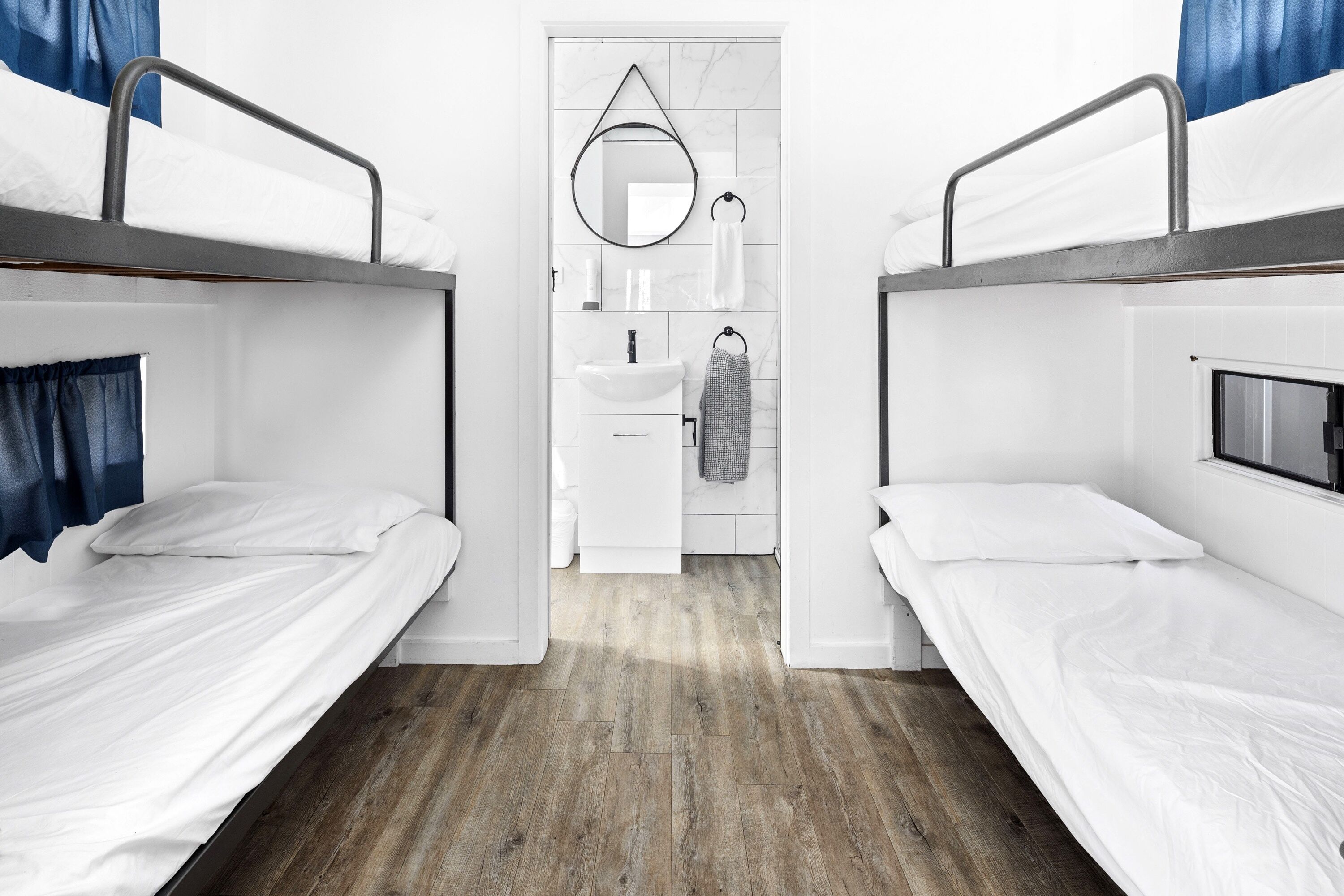 Une chambre avec un lit superposé, une petite salle de bain et un miroir.