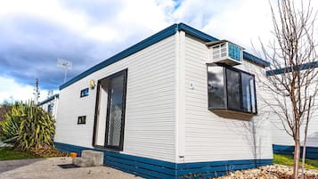 A single-story mobile home with a blue trim, a satellite dish, and a small window.