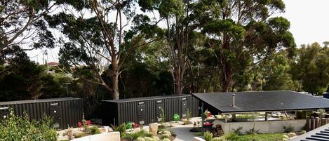 A modern outdoor area with a circular seating area, a covered pavilion, and a view of a residential area in the background.
