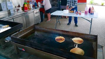 Une cuisine professionnelle équipée d’une plaque de cuisson pour préparer des crêpes, d’un distributeur de boissons gazeuses et d’un four à micro-ondes.