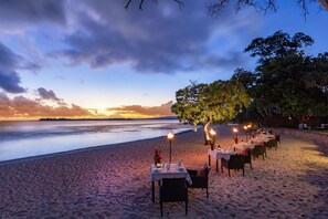 Un comedor frente a la playa, con mesas preparadas para la cena y vistas al mar.