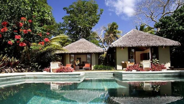 Un complexe hôtelier doté d’une piscine à eau cristalline, de bungalows aux toits de chaume et d’une végétation tropicale luxuriante.