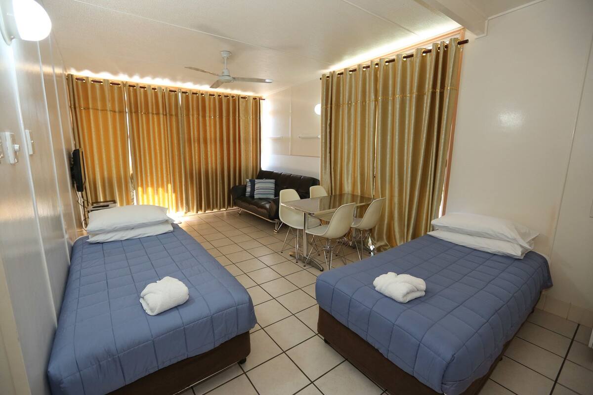 A hotel room with two beds, a small table, and a TV.