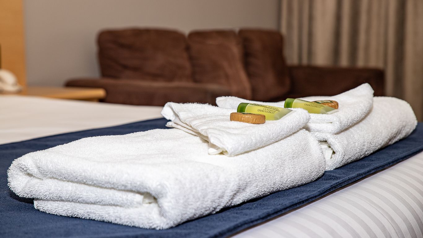Ein ordentlich bezogenes Bett mit weißen Handtüchern und Pflegeprodukten.
