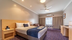 A hotel room with a bed, bedside table, desk, chair, and a ceiling fan. - Albert Motel (Moree)