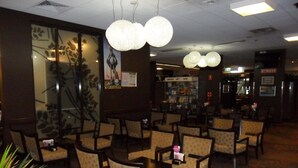 A restaurant with round tables and chairs, hanging light fixtures, and a menu board. - Albert Motel (Moree)