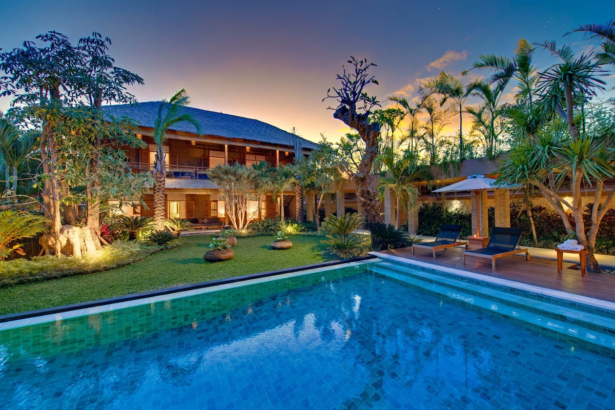 Un resort con piscina, lettini e vegetazione tropicale.
