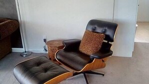 A modern living room with a leather sofa, a matching ottoman, and a floor lamp. - Lakeside City Apartments - Penthouse (Rotorua)