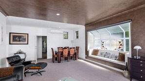 A spacious living room with a dining area, a large window with a view, and a modern fireplace. - Lakeside City Apartments - Penthouse (Rotorua)