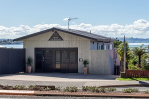 En bygning med skilt der siger "Lakeside City Apartments". Den har en stor garageport, to plantekrukker og udsigt til vand og bakker i baggrunden.