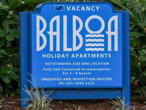 Blaues Schild für das Balboa Holiday Apartments, das eine freie Unterkunft für 1-6 Gäste anzeigt, eine vollständig ausgestattete Ferienwohnung mit Telefonnummer für Anfragen.