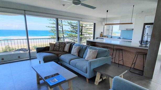 Uma sala de estar moderna com um sofá, mesa de centro e vista para o oceano.