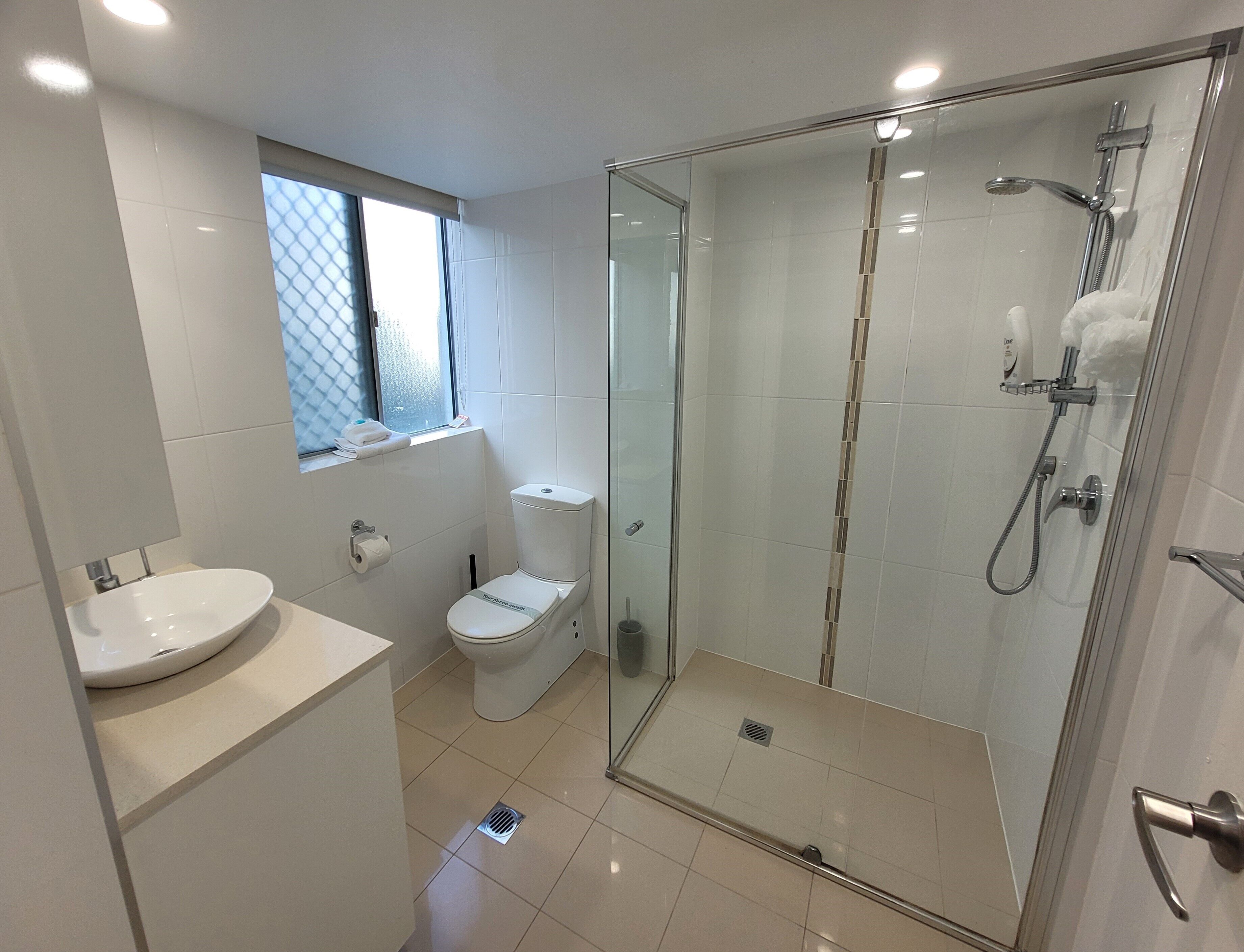 A modern bathroom with a glass-enclosed shower, a toilet, and a sink.