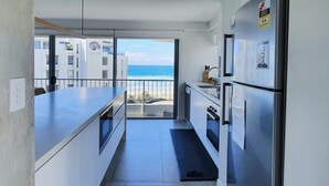 Cozinha moderna com vista para a praia, varanda e geladeira com adesivo.