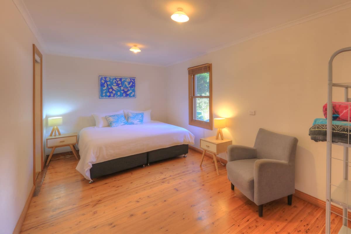 A bedroom with a bed, bedside tables, a chair, a bunk bed, and a window.