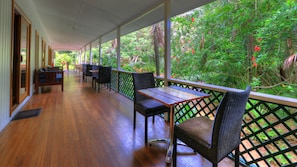 Relax on the veranda with comfortable seating and a view of lush greenery.