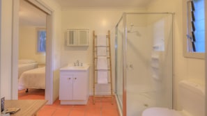 Enjoy a refreshing shower in this bathroom with a clear enclosure, sink, and convenient bedside table.