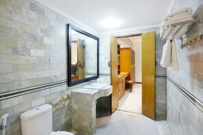 A bathroom with a stone sink, a toilet, a mirror, and a towel rack. - Bali Bungalo Hotel (Legian)
