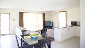 Una habitación de hotel moderna con comedor, sofá, televisor y kitchenette.
