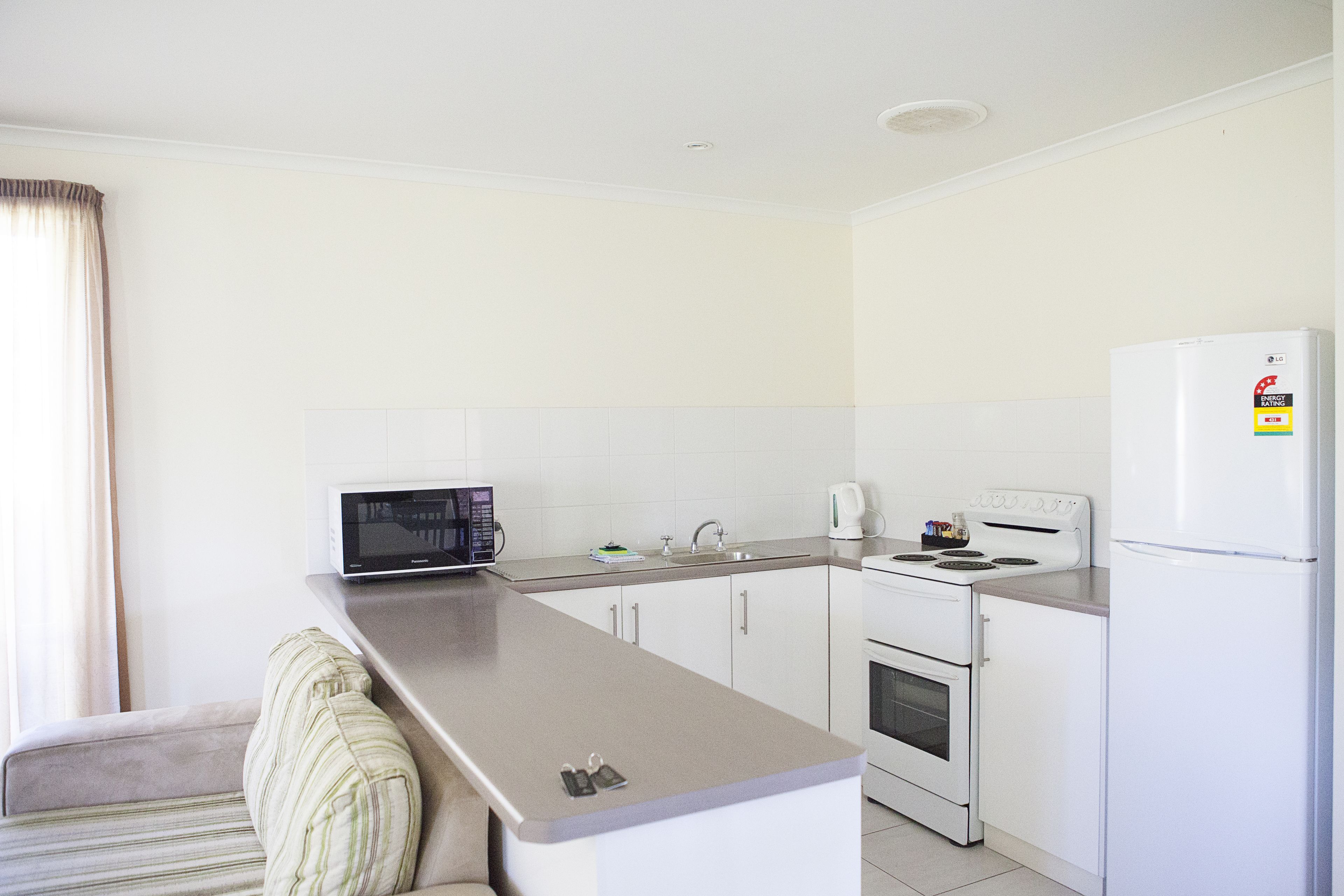 A compact kitchen with a microwave, stove, sink, and refrigerator.