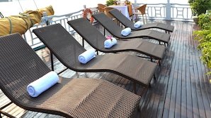 Una terraza con sillones de descanso, una mesa y vistas a una masa de agua.