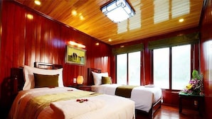 Habitación de hotel con dos camas, suelo de madera, un ventanal grande y un cuadro en la pared.