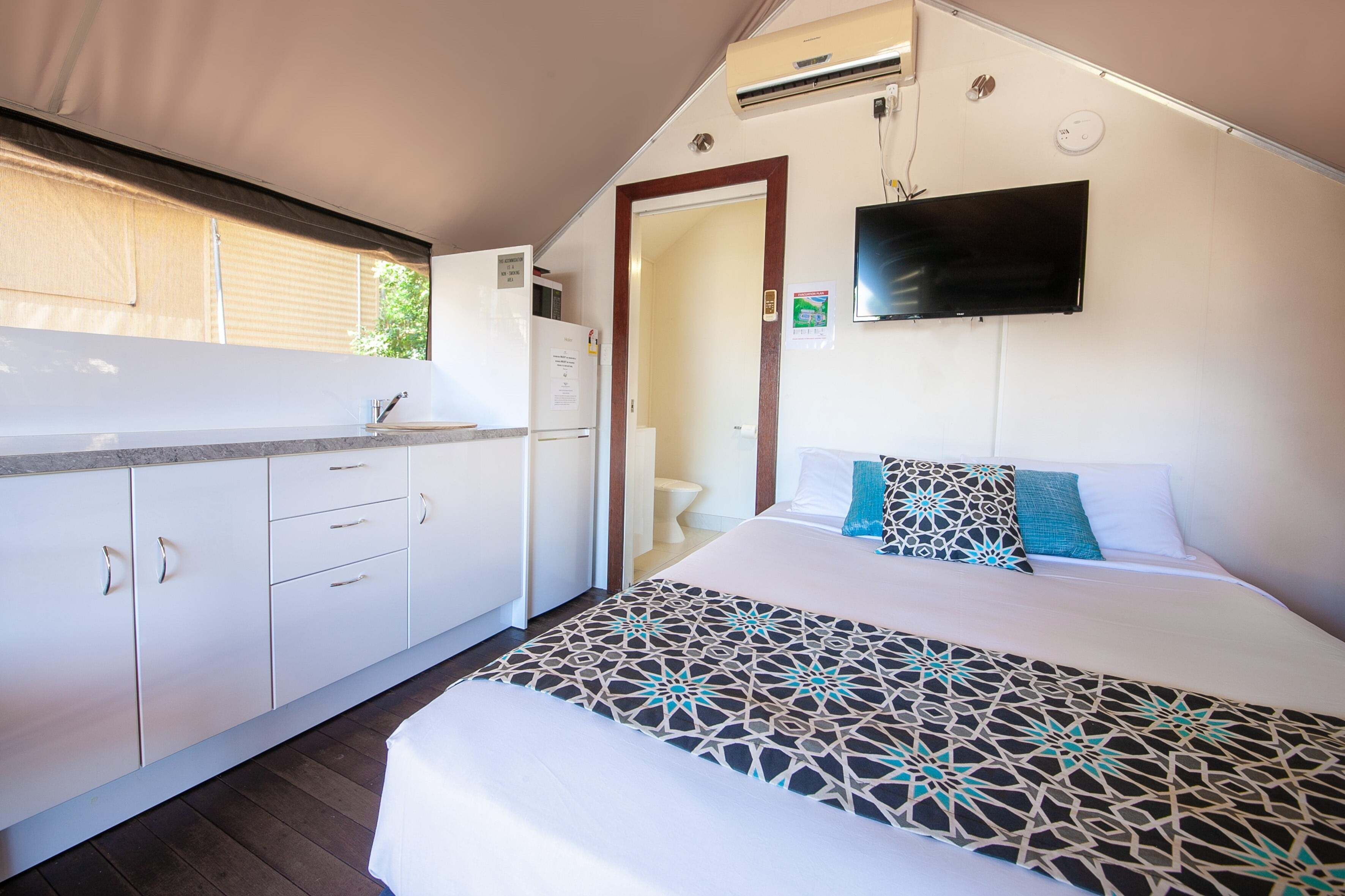 Een slaapkamer met een bed, een televisie en een kitchenette.