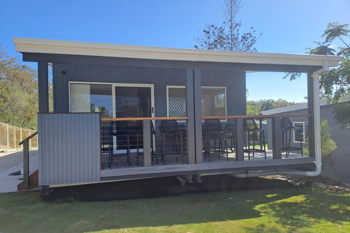 Une maison moderne dotée d’un patio couvert, de grandes fenêtres et d’une terrasse clôturée.