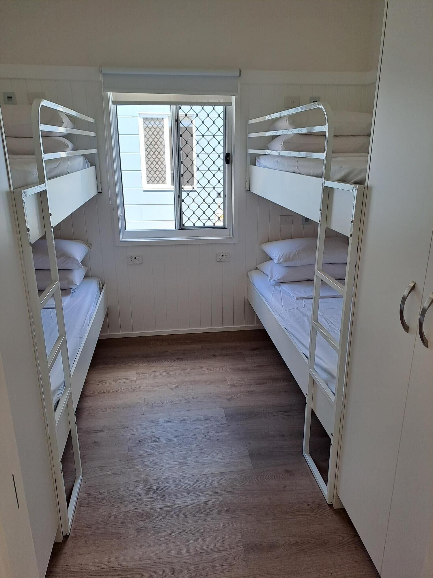 Une chambre avec des lits superposés, une fenêtre donnant sur un beau paysage et un plancher en bois.
