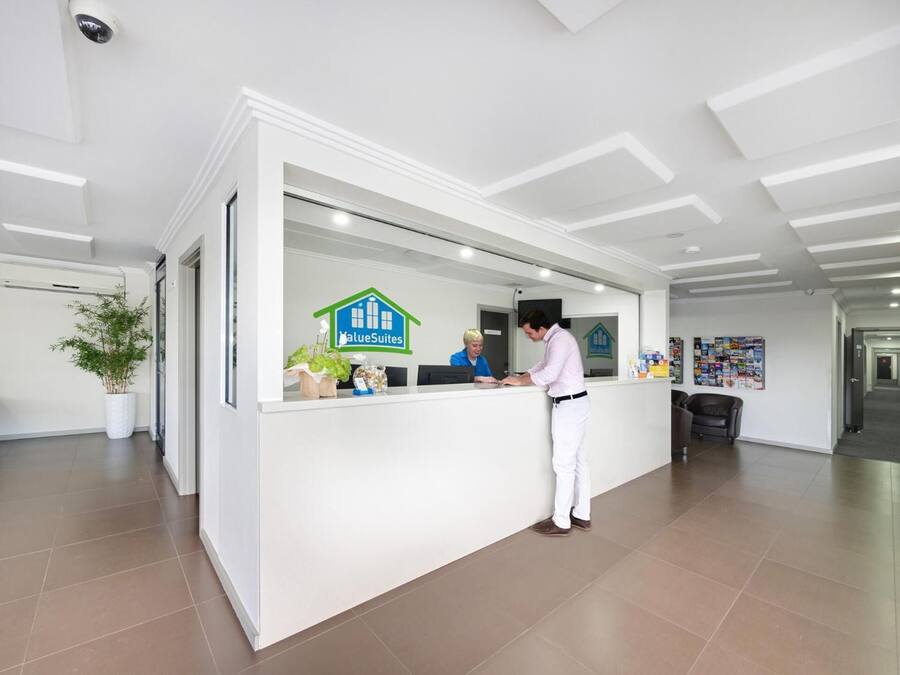 A reception desk with a logo, a potted plant, and a seating area with a couch.