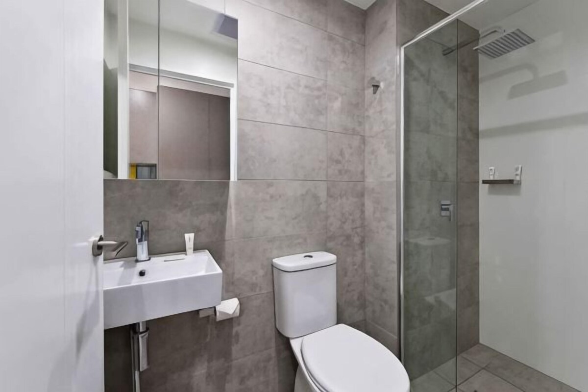 Un baño moderno con lavabo, inodoro y cabina de ducha de vidrio.