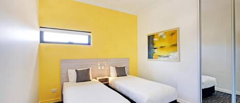 A hotel room with two beds, a ceiling fan, a window, and a painting on the wall.