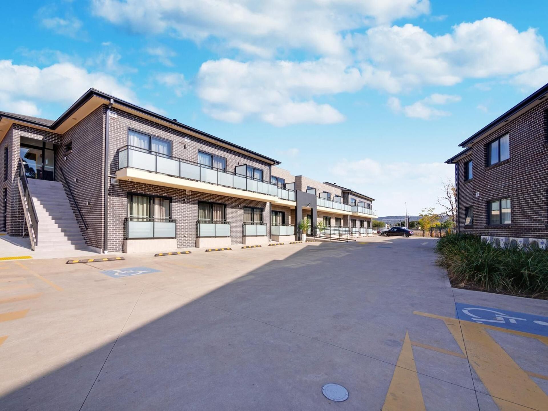 A modern building with a flat roof, large windows, and a covered walkway.