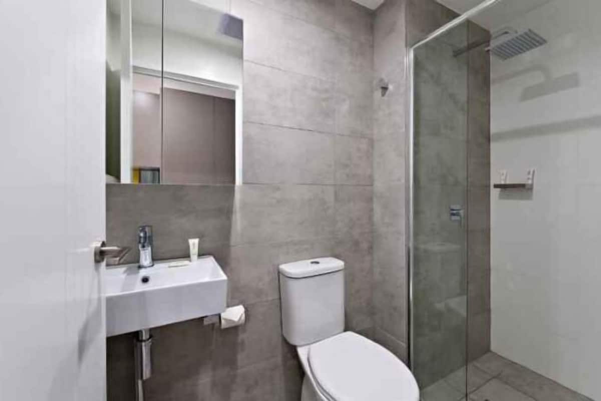 A modern bathroom with a glass shower enclosure, a white sink, and a toilet.