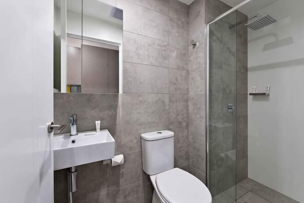 A modern bathroom with a sink, toilet, and glass shower enclosure.