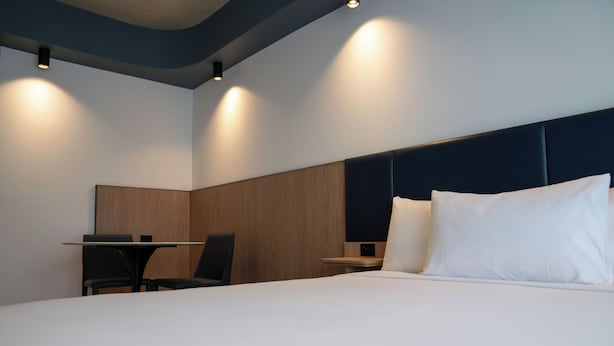 Una habitación de hotel moderna con una cama bien hecha, un escritorio y una silla.