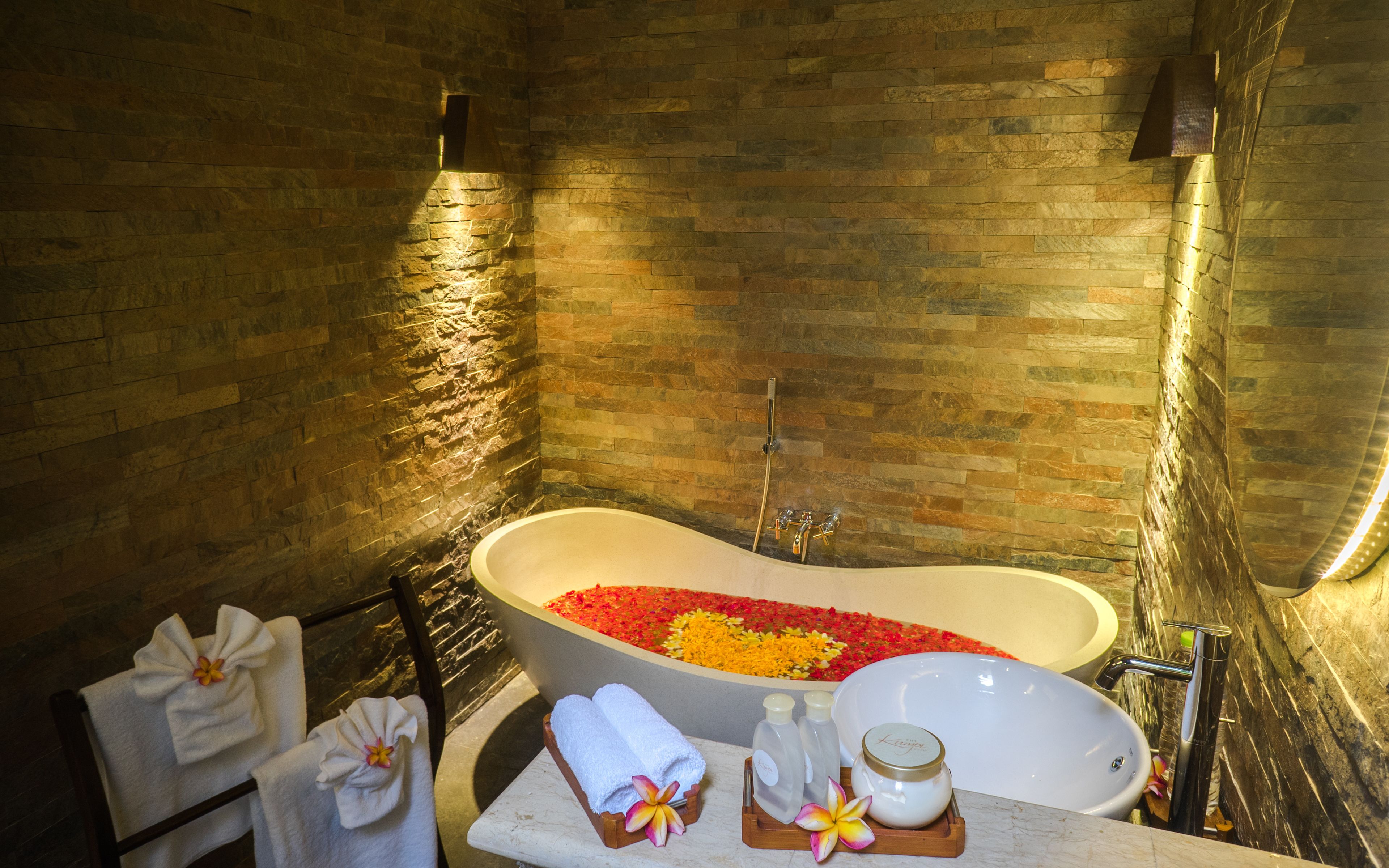 Een spabad met een vrijstaand bad, een wastafel en een douche.
