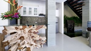 A modern kitchen with white cabinets, a glass island, and a decorative plant arrangement.