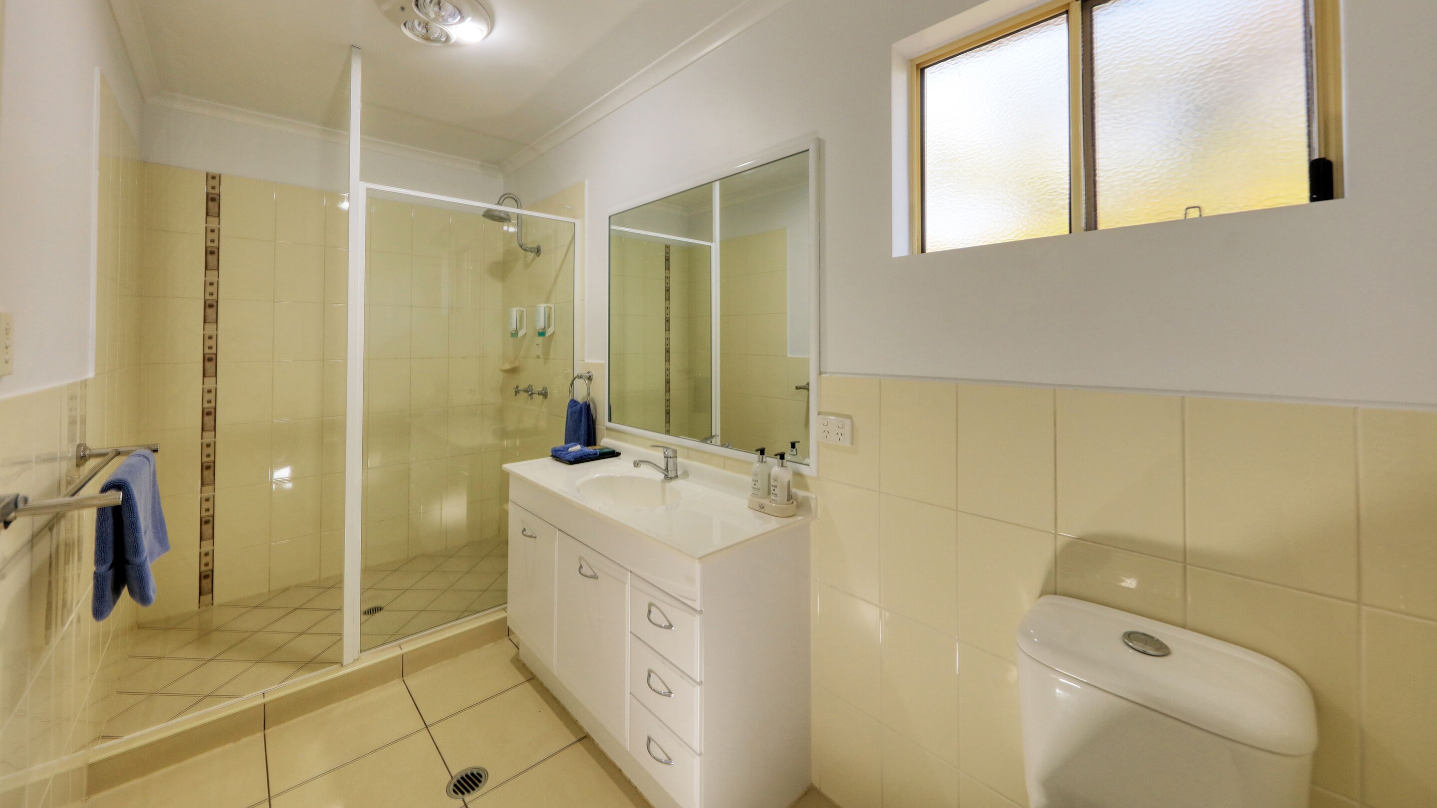A bathroom with a glass shower enclosure, a white sink with a mirror, and a toilet.