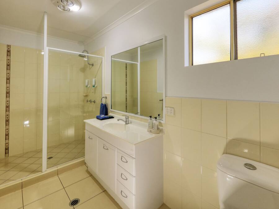 A bathroom with a glass shower enclosure, a white sink with a mirror, and a toilet.